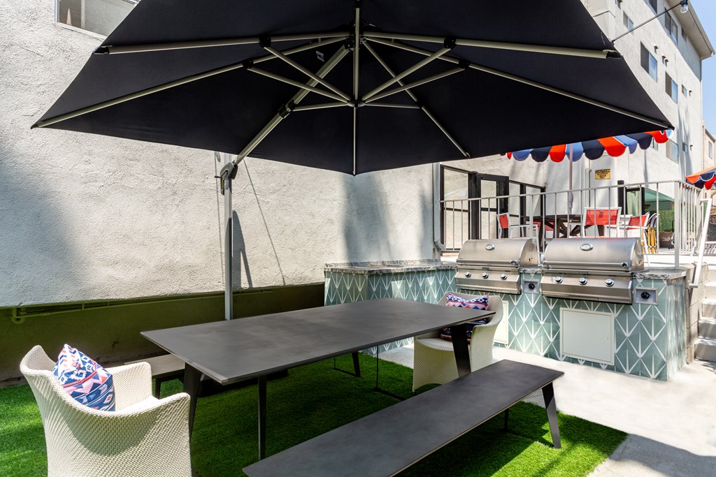 a picnic table with an umbrella and chairs on a backyard patio