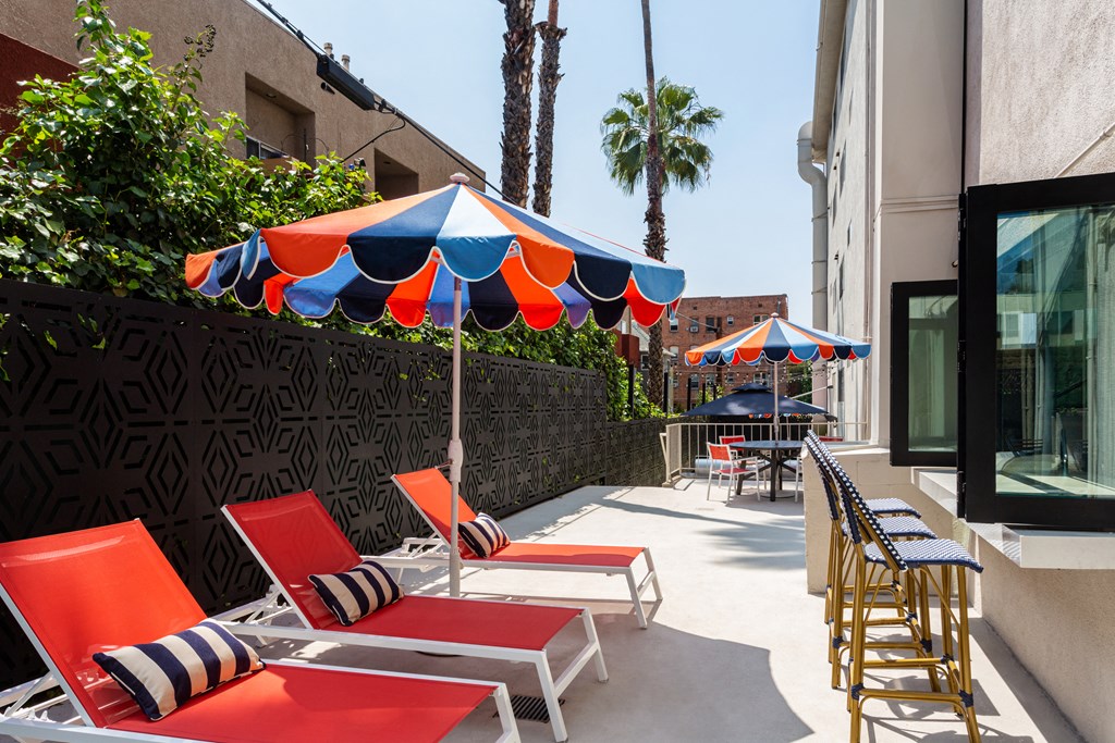 a patio with orange and blue chairs and umbrellas