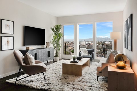 A living room with a chair, a table, a television, and a view of the city.