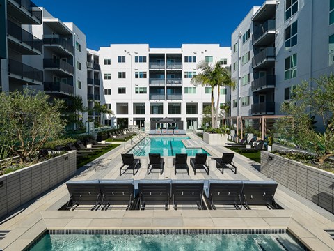 a swimming pool with chairs in front of an apartment building