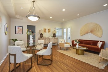 Living area with dining table, seating areas, and a glass door leading outside - Photo Gallery 19
