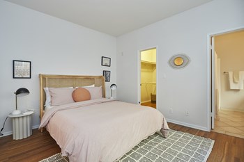 Bright white bedroom with full-sized bed and attached walk-in closet and bathroom - Photo Gallery 14