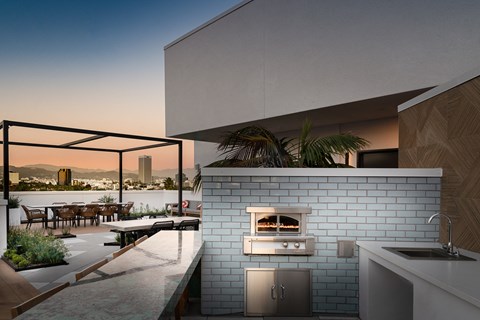 A modern outdoor kitchen with a brick oven and a view of the city.