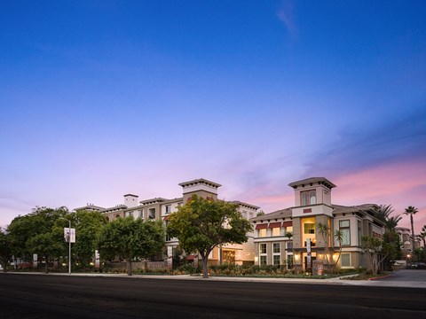 a row of apartment buildings on a city street at sunset