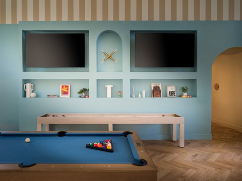 a pool table and two televisions on a blue wall