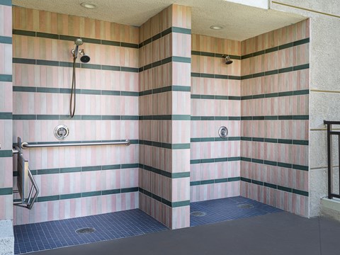 a large shower stall in a public restroom with black and white striped walls