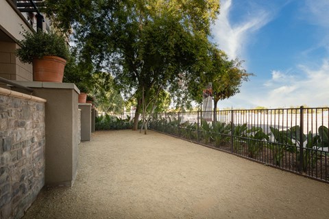 a yard with a fence and trees and plants on the side of a house