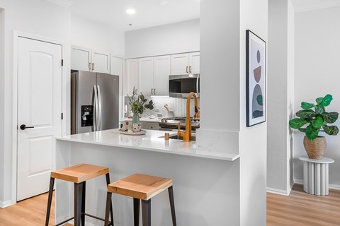 a kitchen with three stools in front of a counter