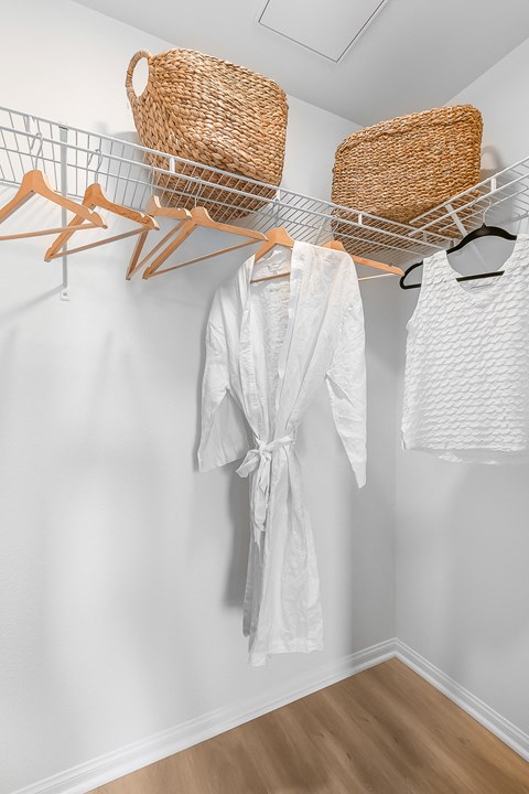 a closet with a white robe and two baskets on the wall