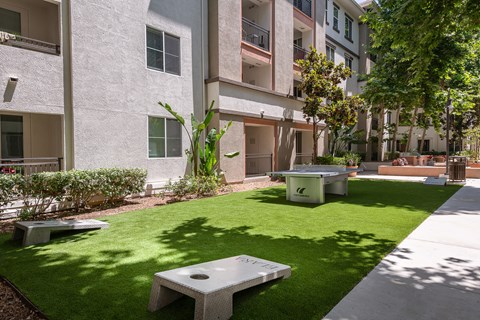 a grassy area with benches and tables in front of an apartment building