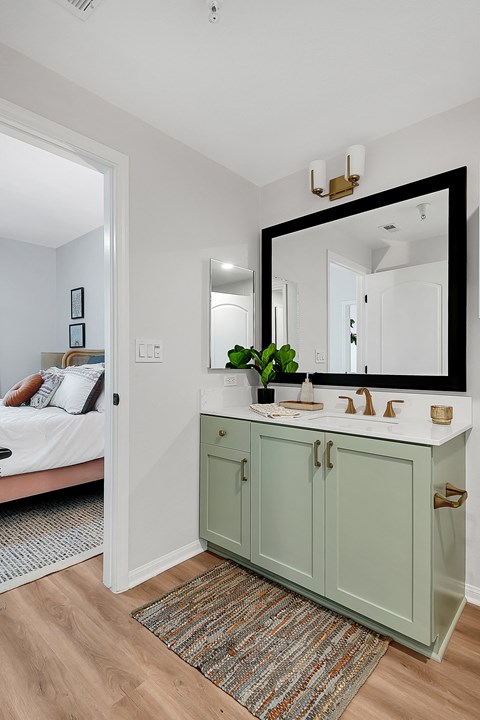 a bathroom with a green vanity and a large mirror