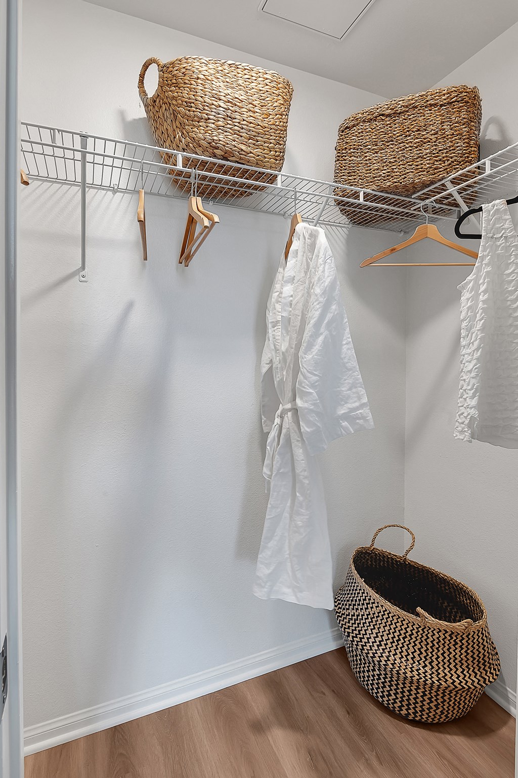 a walk in closet with a white robe hanging on the wall and a basket on the floor