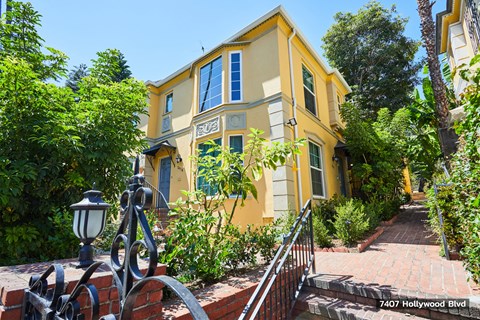 a yellow house with a staircase and a fence in front of it
