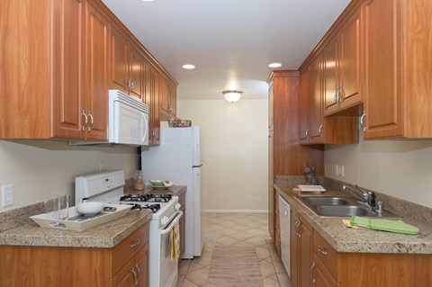 a kitchen with wood cabinets and white appliances and granite counter tops