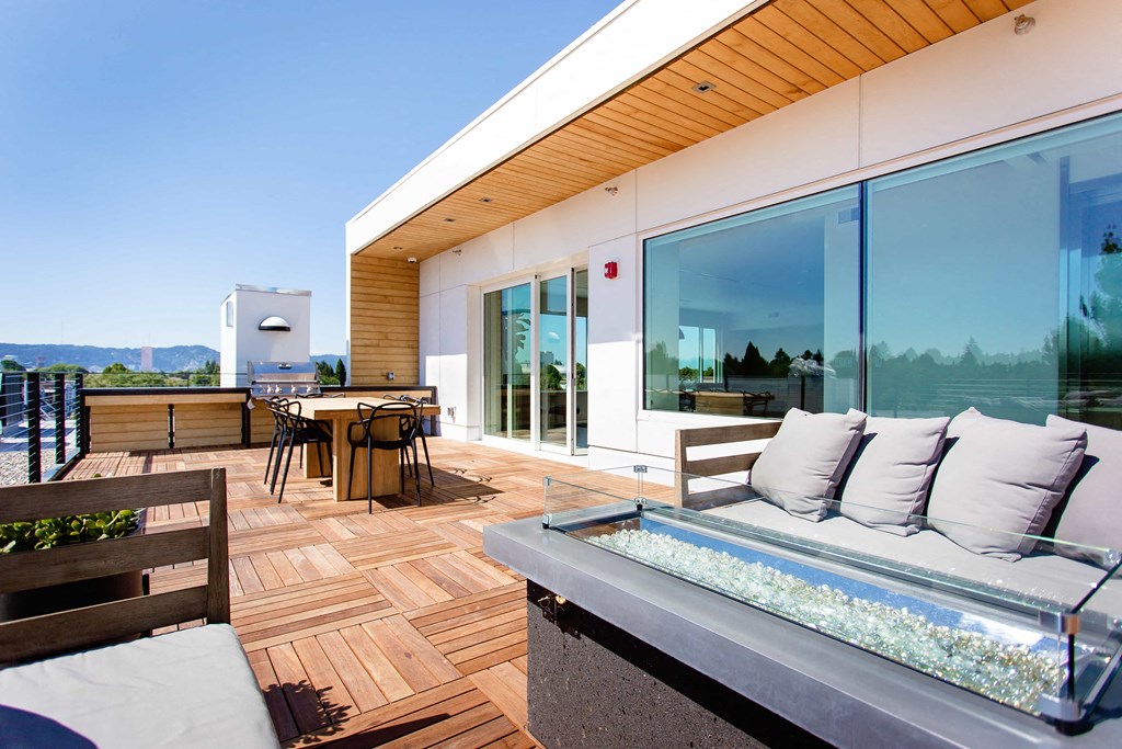 Rooftop outdoor patio with couches, tables, and a BBQ