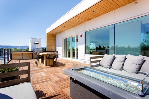 Rooftop outdoor patio with couches, tables, and a BBQ