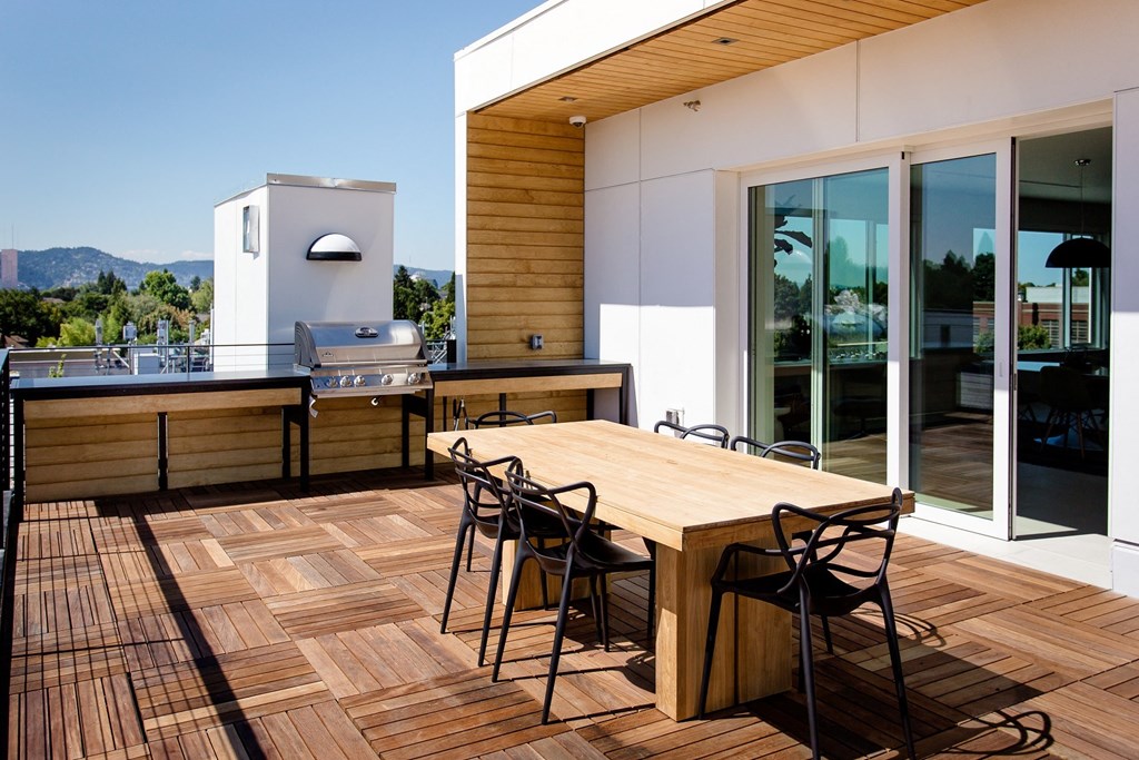Rooftop space overlooking mountains and trees with BBQ, table and chairs