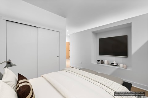 A modern bedroom with a large bed and a flat screen TV mounted on the wall.