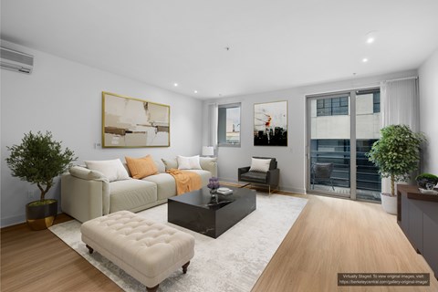 A modern living room with a white sofa, a black coffee table, and a large painting on the wall.