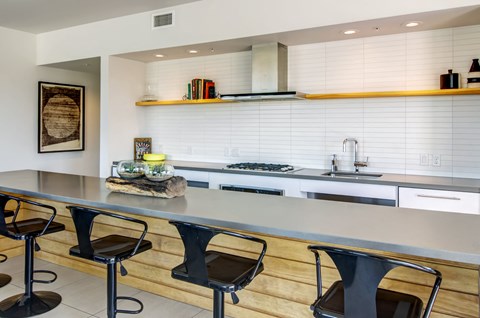a kitchen with a long counter and three chairs