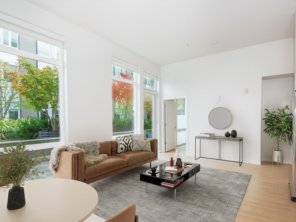 a living room with a couch and a table and large windows
