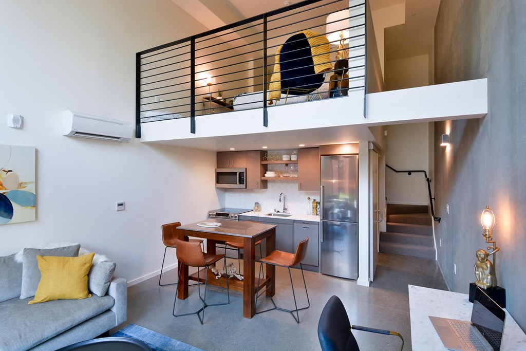 Open floor plan with living area, dining area, kitchen, work space, and stairs leading up to bedroom