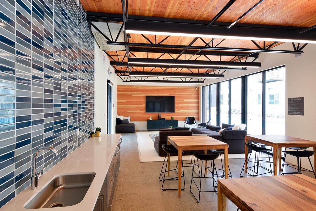 Indoor lounge space with a TV, seating and tables, and a sink
