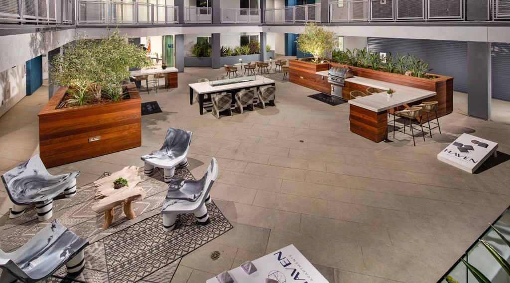 Outdoor lounge area with places to sit, BBQs, and cornhole