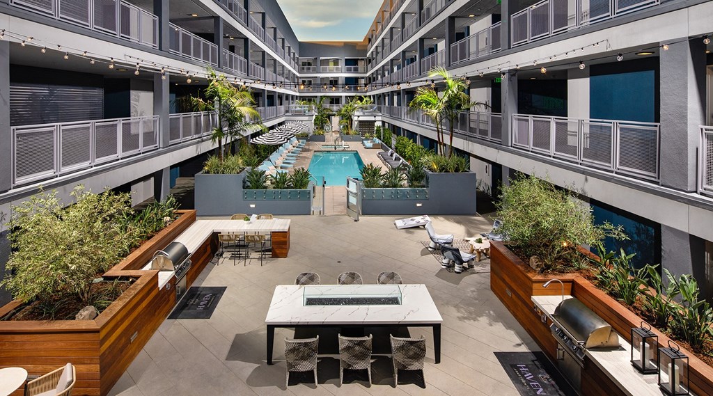 Outdoor courtyard with lounge areas, a pool, BBQs, and hanging lights