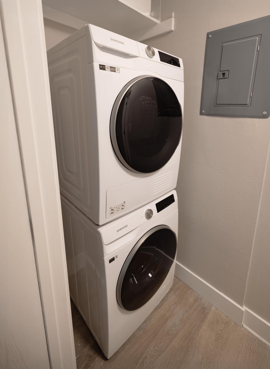 A white front load washing machine is stacked on top of another white front load washing machine.