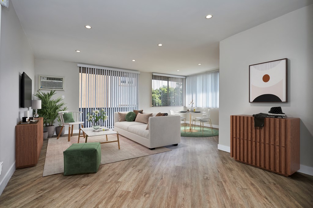 Living room with wooden flooring, large seating areas, and dining area