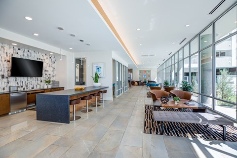 A modern kitchen with a long island and a living area with a couch and a coffee table.