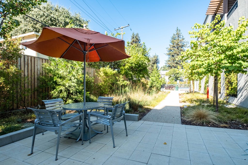 Garden area with table and chairs covered from sub by umbrella