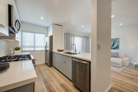 an open kitchen and living room with white walls and wooden floors