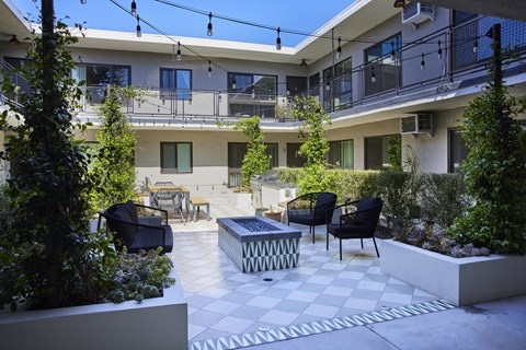 Outdoor lounge in courtyard with firepit, BBQ, and hanging lights