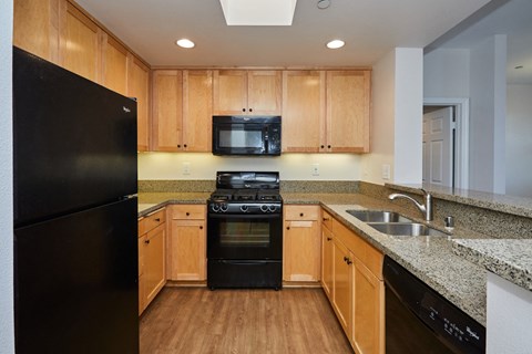 a kitchen with wood cabinets and black appliances and granite counter tops