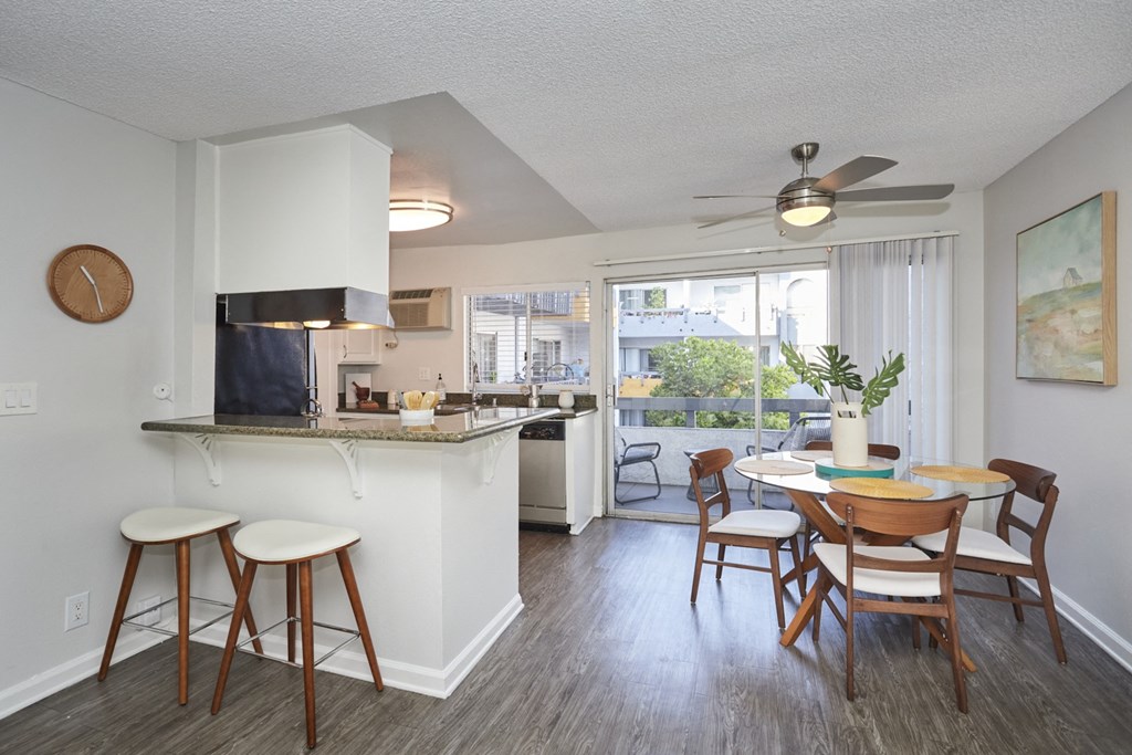 Open Floor Plan with Dining Area, Breakfast Bar, and Kitchen Next to Balcony