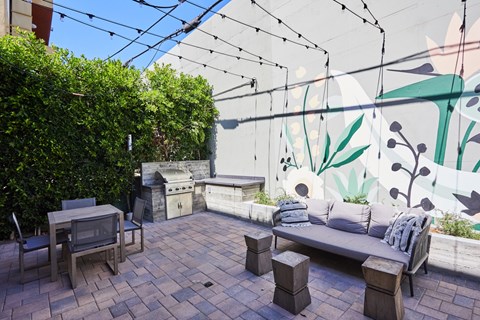 A patio with a table, chairs, and a bench with a cushion.