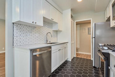 a kitchen with white cabinets and a stainless steel dishwasher