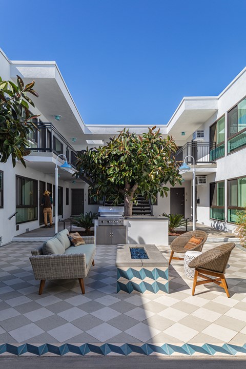 Outdoor courtyard with fireplace, seating, and BBQ