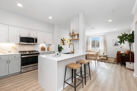 a kitchen with white cabinets and a large white island with two stools in front of it