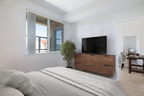 A bedroom with a large bed and a flat screen TV mounted on the wall.