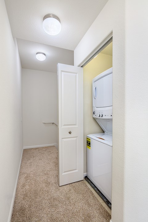 A white door is open to a small kitchen with a white refrigerator.