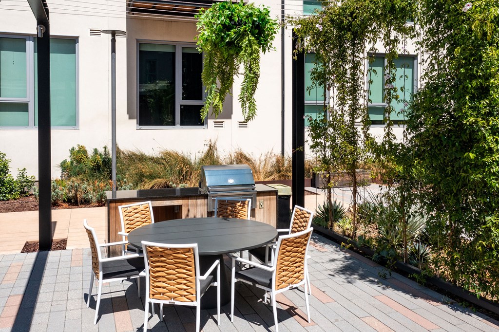 a patio with a table and chairs and a grill