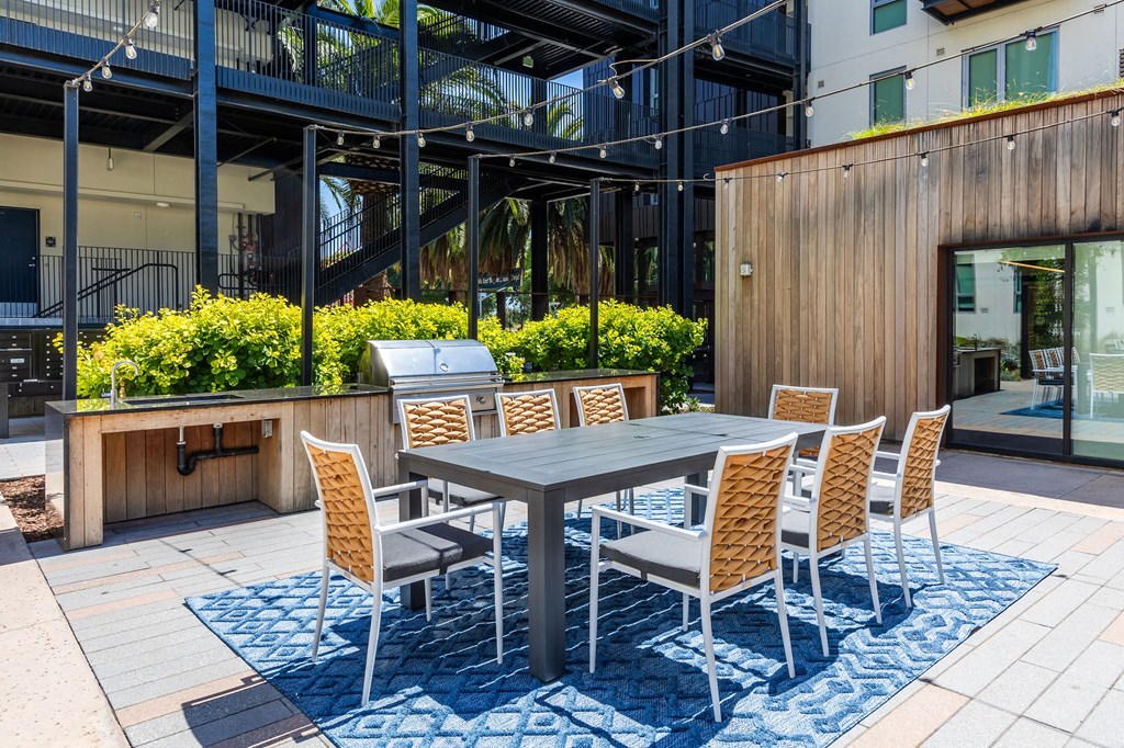 a patio with a table and chairs and a grill