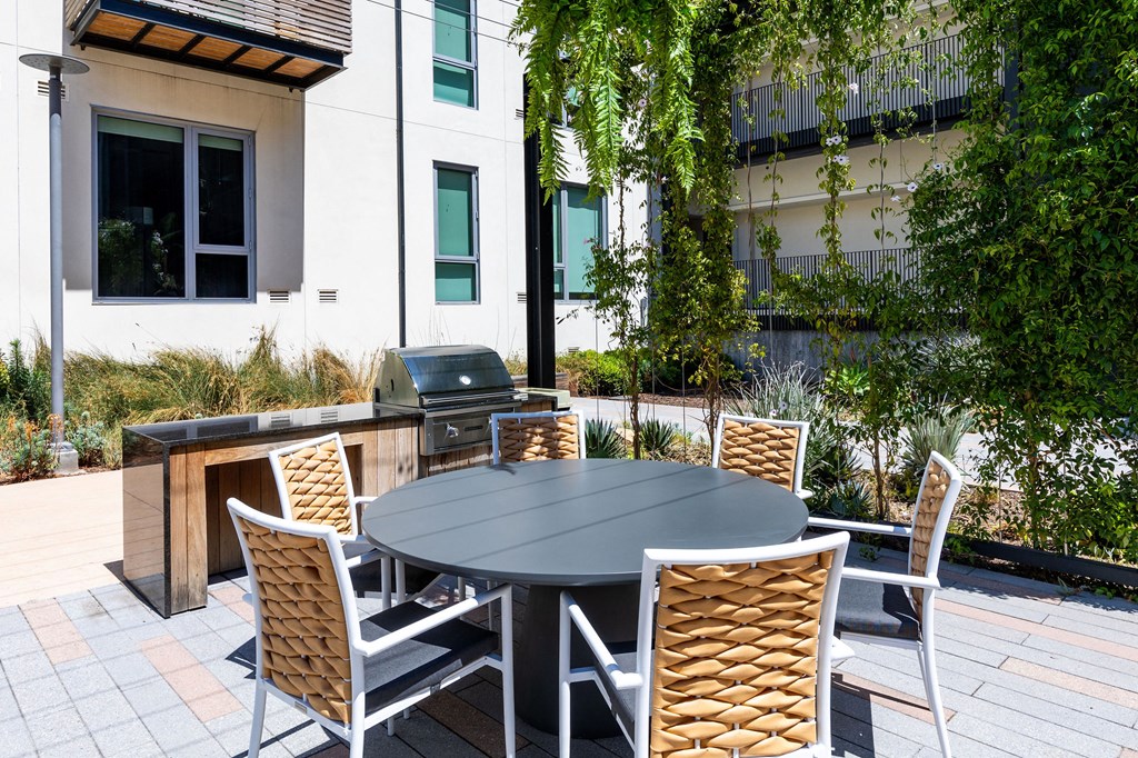 a patio with a table and chairs and a grill