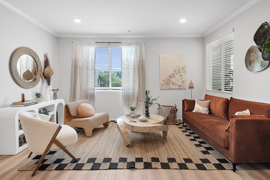 a living room with a brown couch and two white chairs