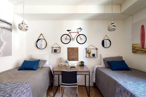 a bedroom with two beds and a table and a bike on the wall