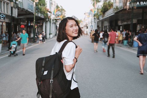 a woman walking down a city street with a backpack