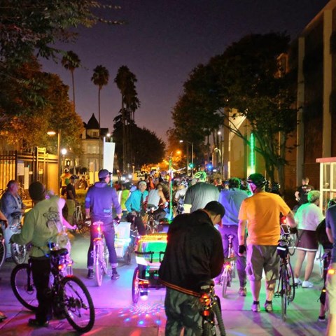 a group of people riding bikes down a street at night